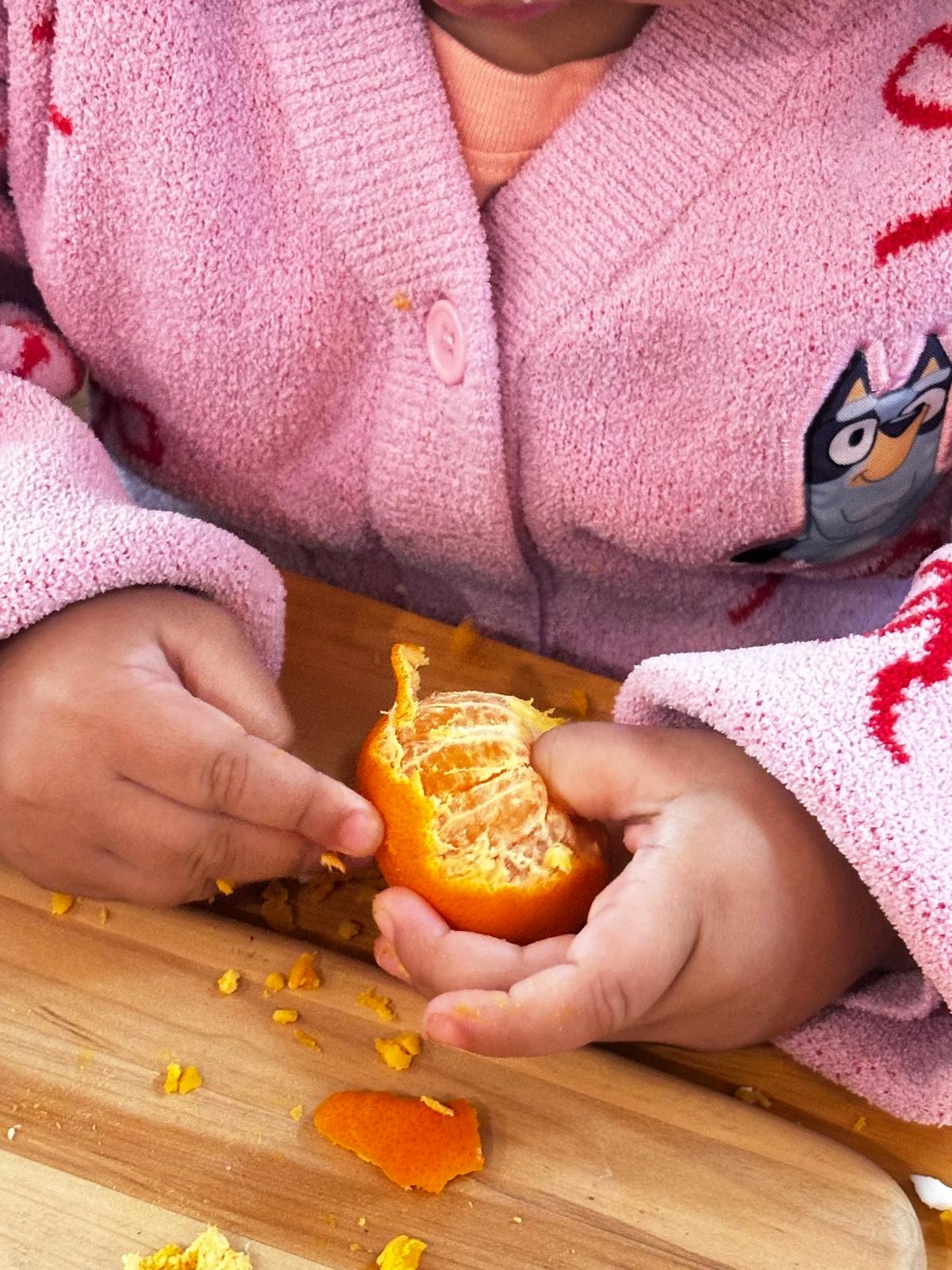 Little hands peeling a mandarin